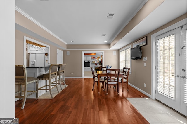 dining area featuring crown molding, wood finished floors, visible vents, and baseboards