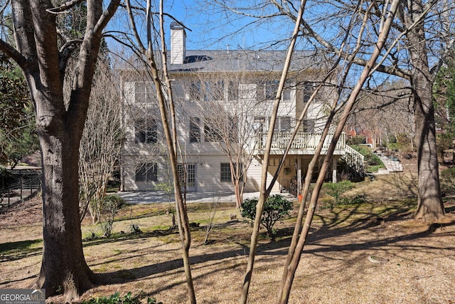 back of property featuring a chimney, stairs, and a patio