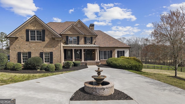 view of front facade featuring brick siding, a chimney, a front lawn, and fence