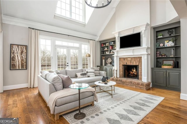 living room featuring french doors, high vaulted ceiling, wood finished floors, and a fireplace