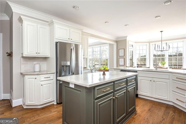 kitchen with a sink, dark wood-style floors, crown molding, and white cabinetry