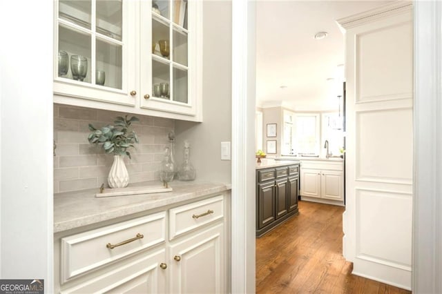 bar featuring a sink, decorative backsplash, and dark wood finished floors