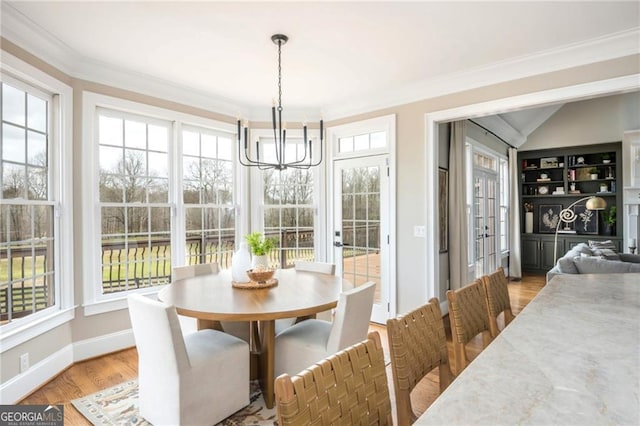 dining space featuring plenty of natural light, crown molding, and light wood finished floors