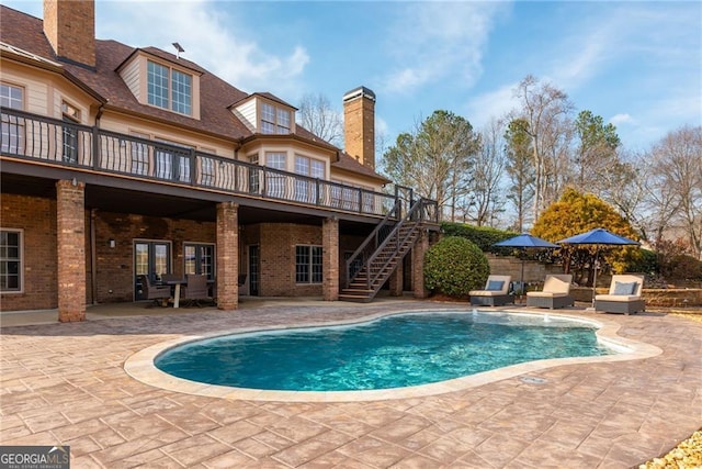 pool featuring stairway, a wooden deck, and a patio area