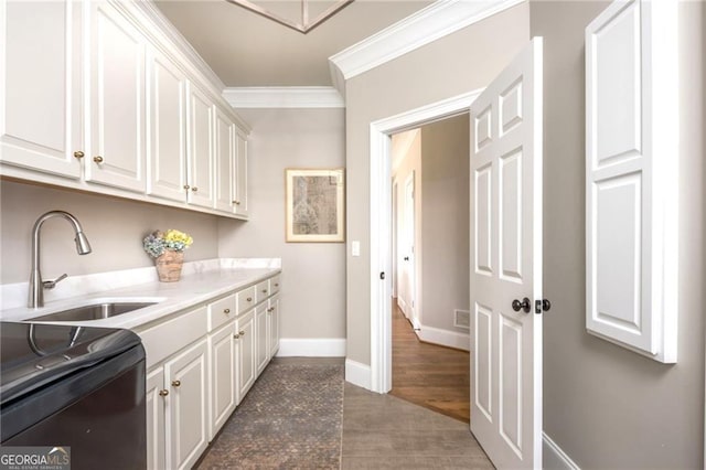 kitchen with baseboards, light countertops, ornamental molding, white cabinetry, and a sink