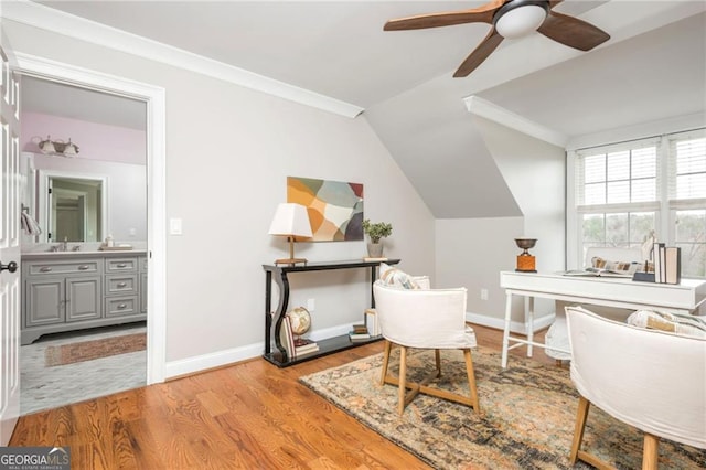 home office featuring wood finished floors, baseboards, lofted ceiling, a sink, and crown molding