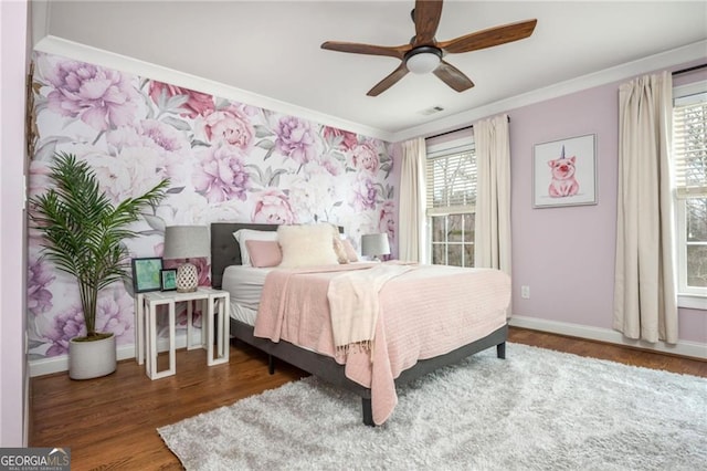 bedroom with baseboards, multiple windows, wood finished floors, and crown molding