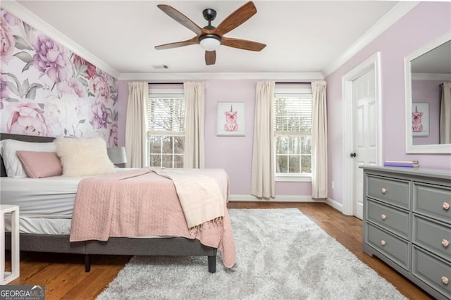 bedroom featuring multiple windows, wood finished floors, visible vents, and ornamental molding