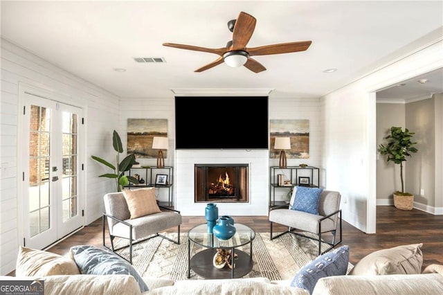 living area featuring wood finished floors, french doors, visible vents, and a lit fireplace