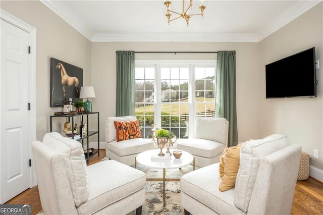 living area featuring wood finished floors, baseboards, a chandelier, and ornamental molding