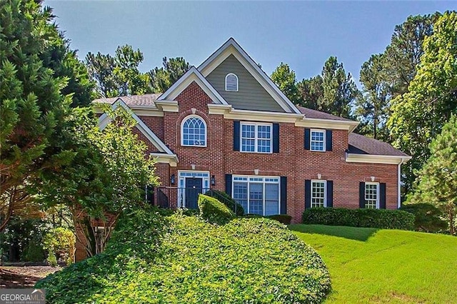 colonial inspired home featuring a front yard and brick siding