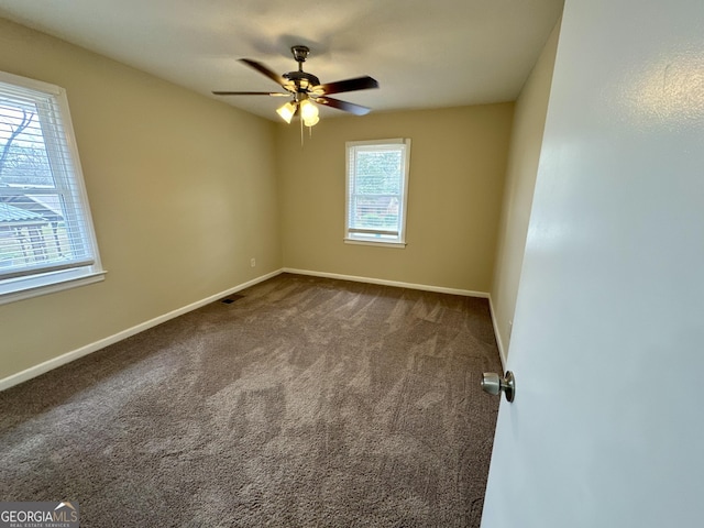 unfurnished room featuring dark colored carpet, visible vents, baseboards, and ceiling fan