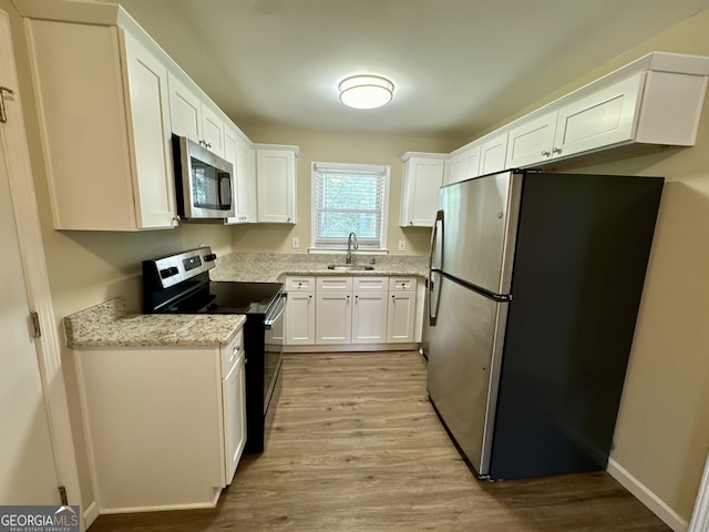 kitchen with white cabinetry, a sink, light wood-style floors, and stainless steel appliances