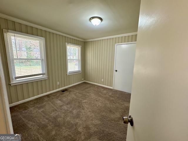 empty room with visible vents, baseboards, carpet, and ornamental molding