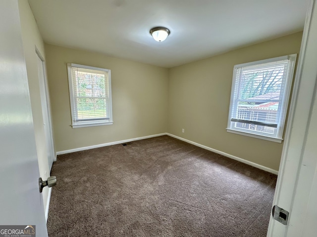 unfurnished room featuring baseboards and dark colored carpet