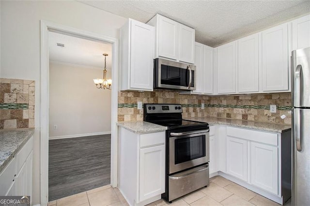 kitchen with light tile patterned floors, white cabinets, stainless steel appliances, and tasteful backsplash