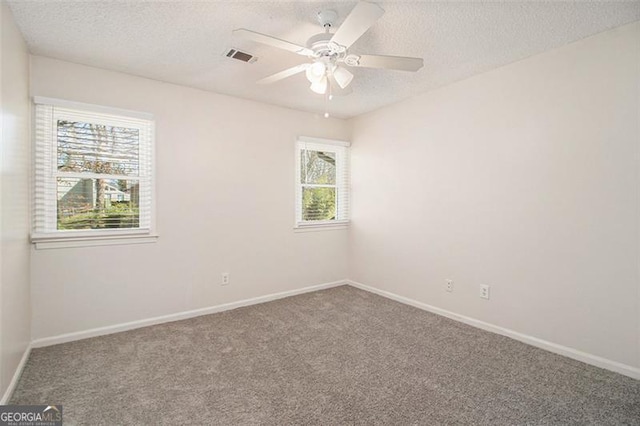 spare room featuring visible vents, a ceiling fan, a textured ceiling, carpet flooring, and baseboards