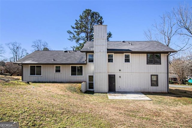 rear view of property featuring a yard, a chimney, and a patio area