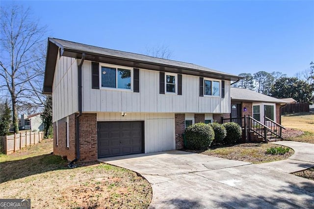 tri-level home with a garage, fence, brick siding, and driveway