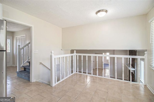 interior space with a wealth of natural light, tile patterned floors, a textured ceiling, and baseboards