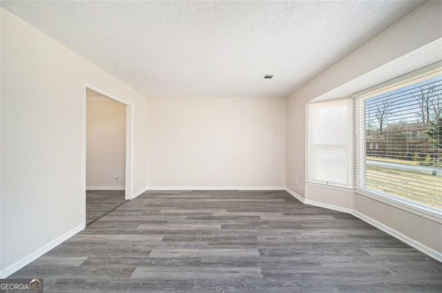 empty room featuring baseboards, a textured ceiling, and wood finished floors