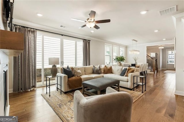 living area with hardwood / wood-style floors, visible vents, and ornamental molding