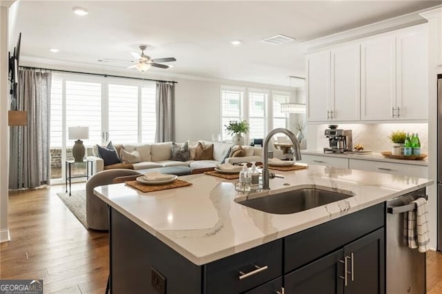 kitchen with dishwasher, white cabinets, open floor plan, and a sink