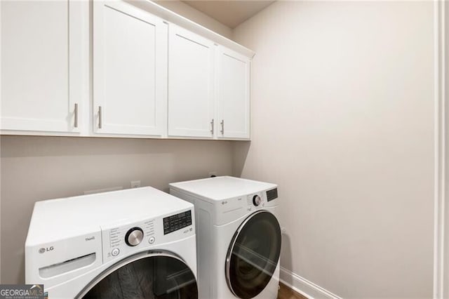 washroom with washing machine and clothes dryer, cabinet space, and baseboards