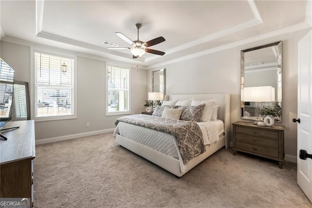 bedroom with a tray ceiling, light carpet, baseboards, and crown molding