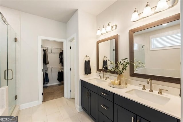 bathroom featuring double vanity, a stall shower, a spacious closet, and a sink