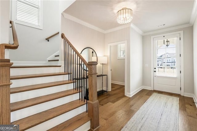 foyer entrance featuring crown molding, baseboards, stairs, an inviting chandelier, and wood finished floors