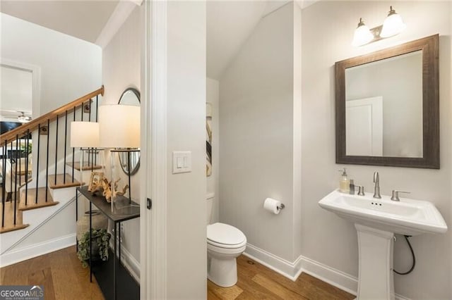 bathroom with toilet, wood finished floors, baseboards, and a sink