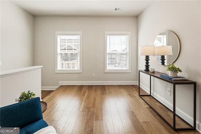 living area featuring visible vents, baseboards, and hardwood / wood-style floors