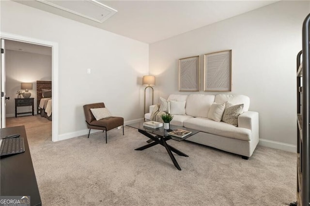 carpeted living area with baseboards and attic access