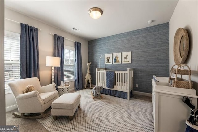 bedroom featuring baseboards, visible vents, wallpapered walls, an accent wall, and carpet flooring