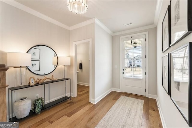 interior space with baseboards, wood finished floors, visible vents, and ornamental molding