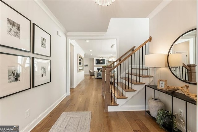 foyer with baseboards, wood finished floors, stairs, and ornamental molding