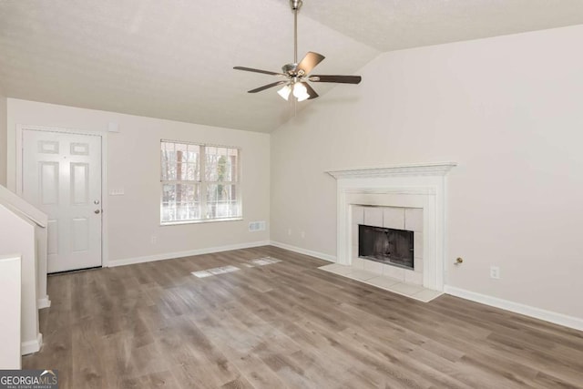 unfurnished living room with a fireplace, baseboards, lofted ceiling, and wood finished floors