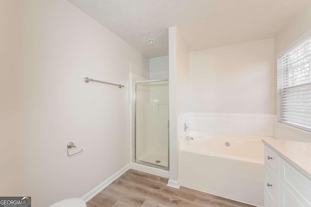 full bath featuring wood finished floors, a shower stall, baseboards, a bath, and vanity