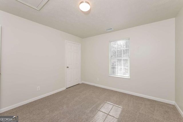 unfurnished room featuring visible vents, carpet floors, a textured ceiling, and baseboards