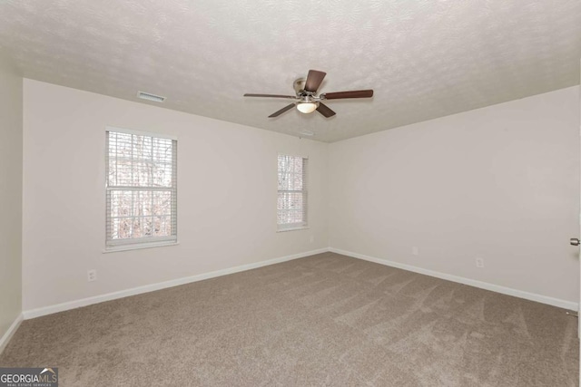 spare room with visible vents, a textured ceiling, carpet flooring, baseboards, and ceiling fan