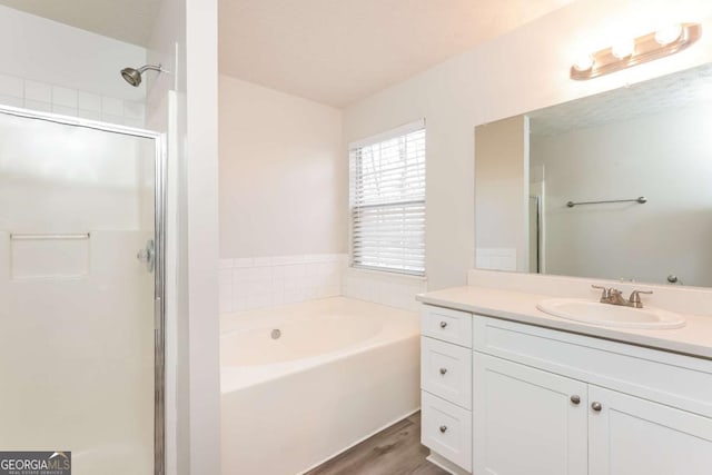 bathroom featuring vanity, a bath, wood finished floors, and a stall shower