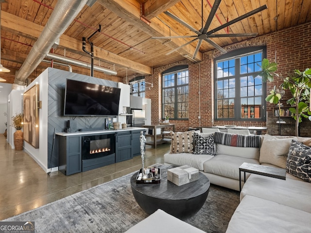 living area featuring a glass covered fireplace, brick wall, wooden ceiling, and a towering ceiling