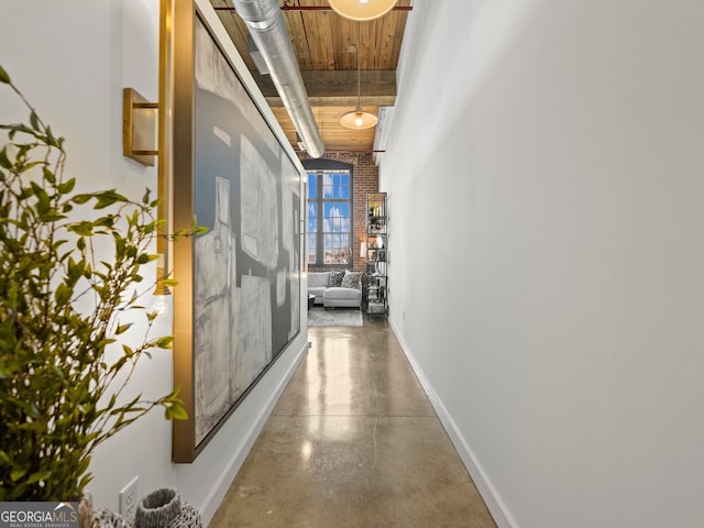 corridor featuring finished concrete flooring and baseboards