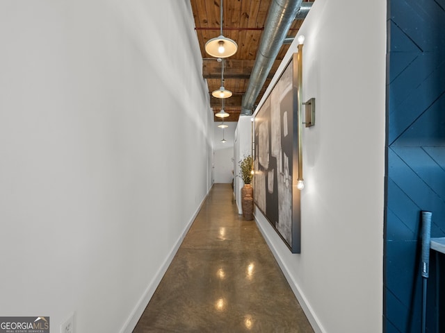 corridor with finished concrete flooring and baseboards