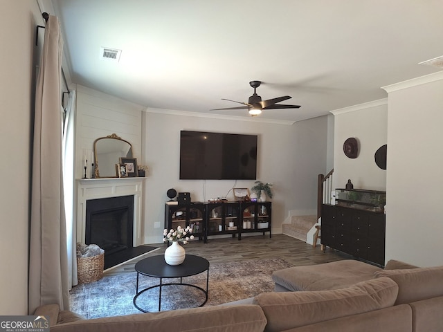 living area with visible vents, stairway, wood finished floors, and ornamental molding