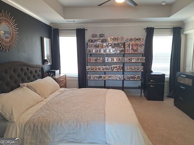 carpeted bedroom with visible vents, a raised ceiling, a ceiling fan, and ornamental molding