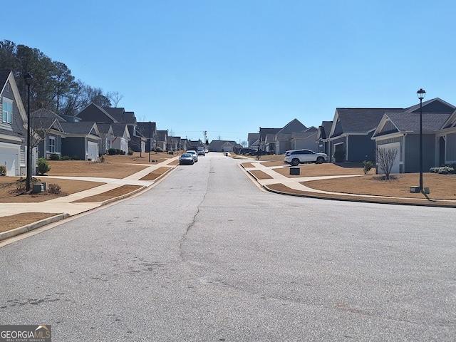 view of road with sidewalks, curbs, a residential view, and street lights