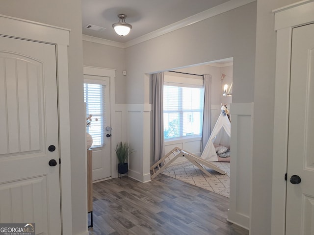 entryway featuring crown molding, wood finished floors, a healthy amount of sunlight, and visible vents