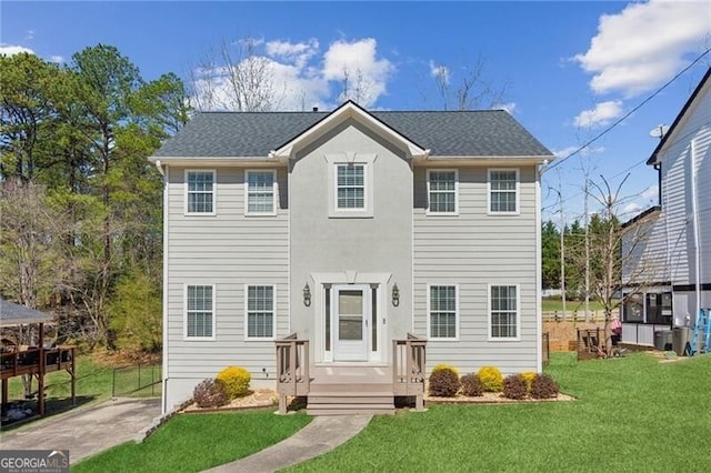 colonial home featuring a front lawn and roof with shingles